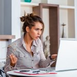 Young businesswoman misunderstanding her laptop at her desk in office. woman working with laptop at home or modern office. Serious, confused, or frustrated expression.